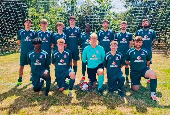 A Painswick FC squad in green Maple Leaf kit, lined up in front of the goal