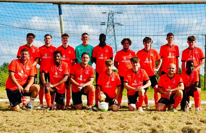 A Painswick FC squad in orange Maple Leaf kit, lined up in front of the goal
