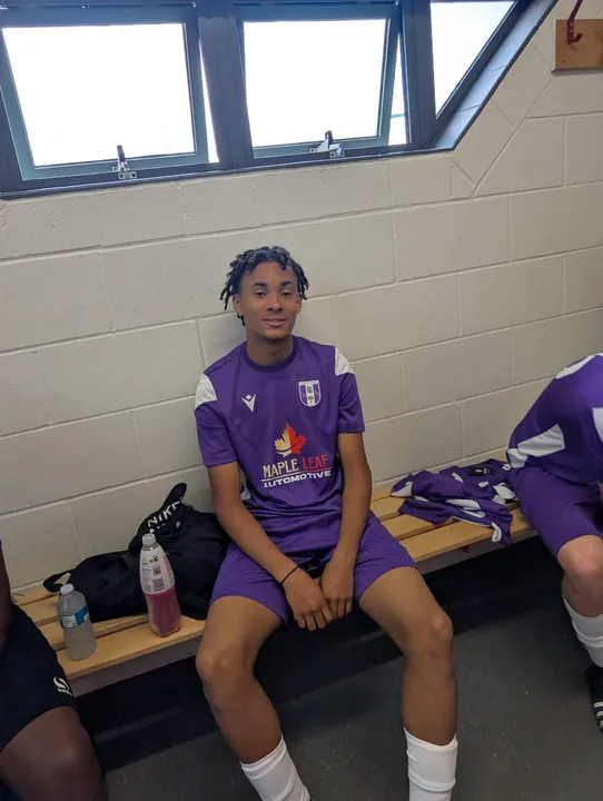 A young player seated in the purple Maple Leaf Automotive kit